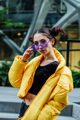 woman in yellow puffer coat and purple sunglasses by Thomas Le on Unsplash