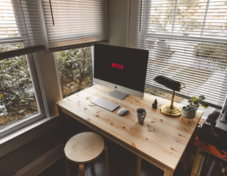 Netflix is displayed on a desktop computer on a table in an aesthetic office.
