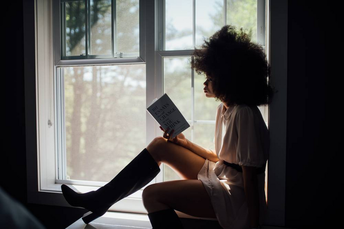 Woman reading on window ledge