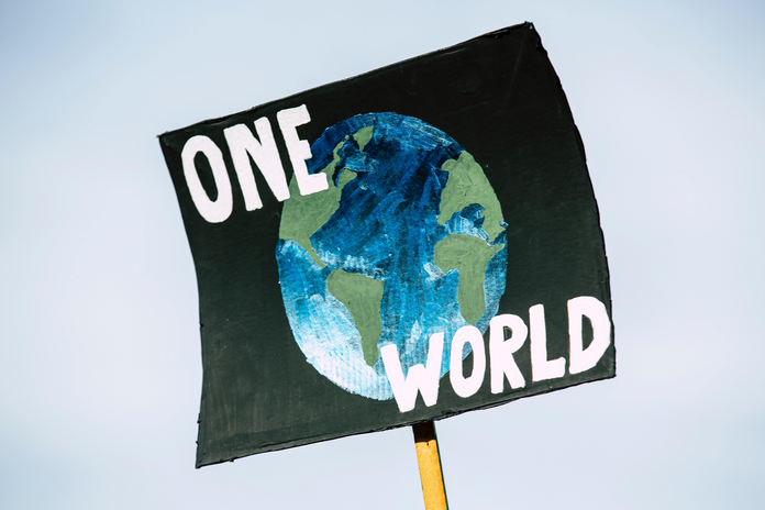a poster sign with \"one world\" written on it, with a globe painted on it