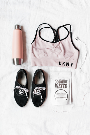 Sports bra water bottle shoes and coconut water by Unsplash