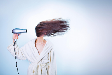 A woman\'s hair is blown by a hair dryer.
