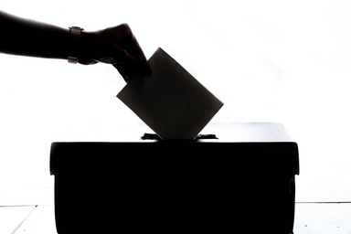 silhouette of a person putting a ballot in a box