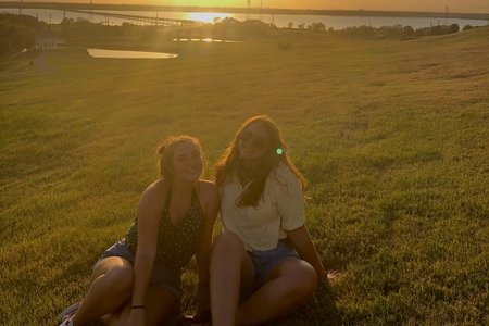 Two girls sitting by sunset
