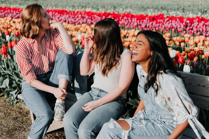 three women laughing in flower field by Priscilla Du Preez