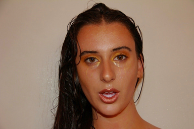 woman staring at the camera with gold makeup and her mouth slightly open
