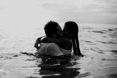 man and woman kissing in water black and white picture