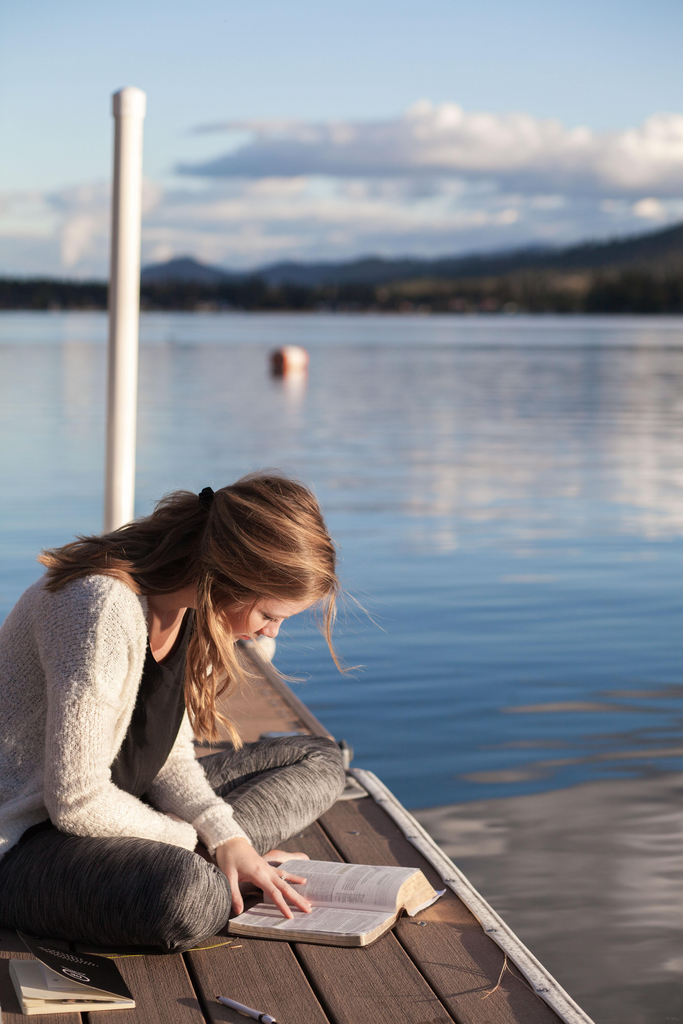 woman reading book on dock
