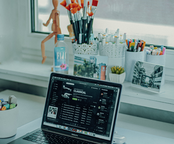 laptop screen displaying Spotify playlist at a desk.