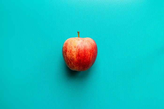 apple on blue surface by Louis Hansel