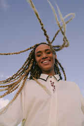 black woman with long blond braids smiling outside