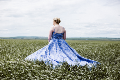 woman standing in long dress on green grass field