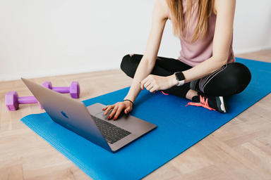 woman on workout mat with laptop