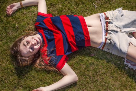 girl in sun in g rass ripped jeans