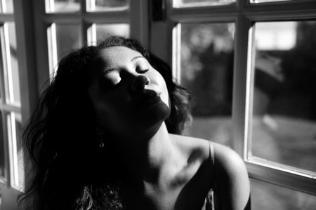 girl sitting by window in black and white