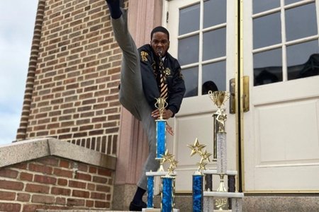 man is holding his leg up with trophies infront of him
