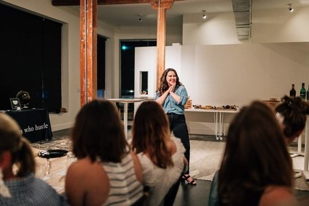 woman standing in front of group of people, hands together