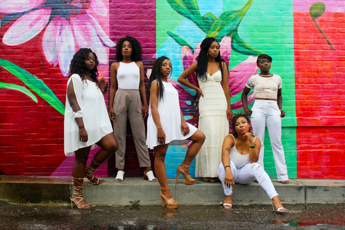 powerful women standing in front of a mural in white with friends