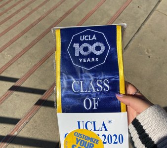 hand holding a ucla class of 2020 sash inside packaging