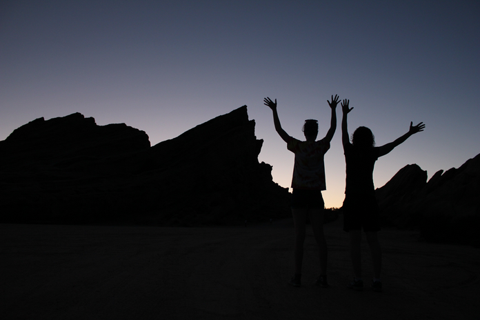 silhouette of two people and rocks