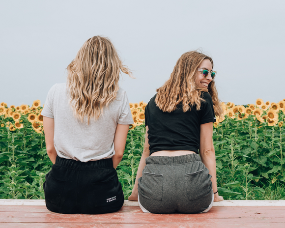 two girls sitting in front of a sunflower field