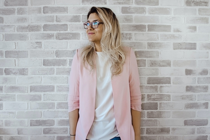 woman in pink cardigan and white shirt leaning on the wall 975657