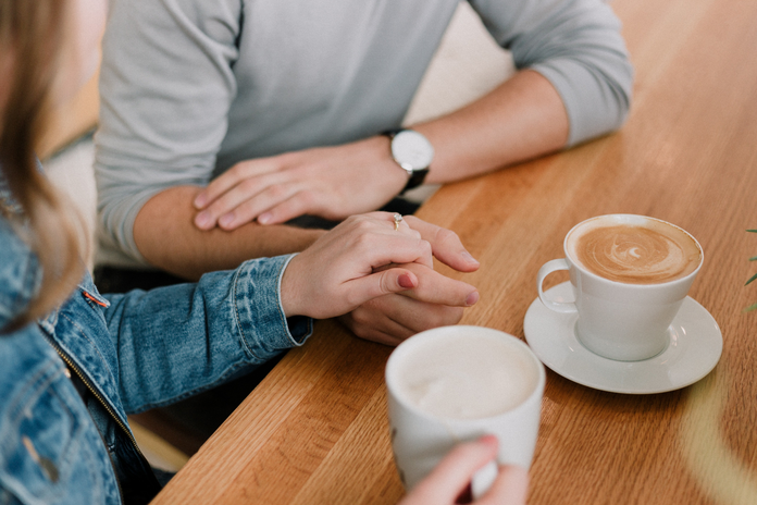 couple holding hands while drinking coffee by unsplash