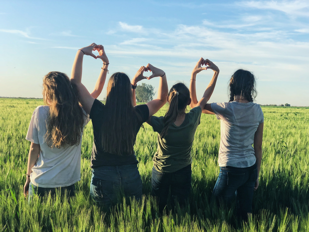 4 women holding up hearts in a field