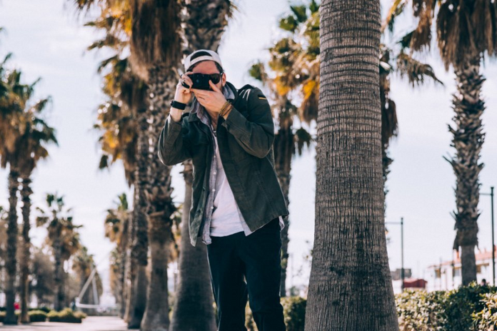 guy taking picture, palm trees in back
