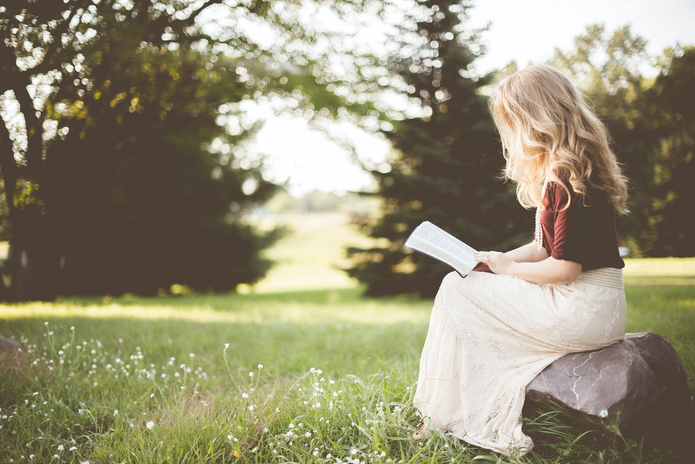 woman sitting in a field reading