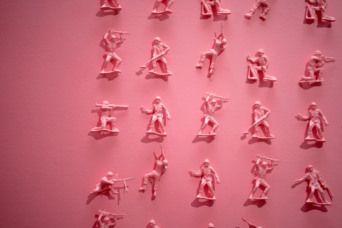 tiny pink toy soldiers on a pink wall