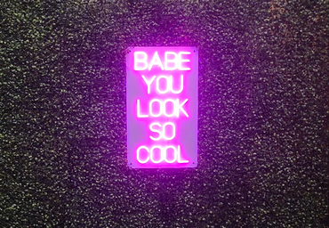 Pink neon sign that says \"Babe you look so cool\"
