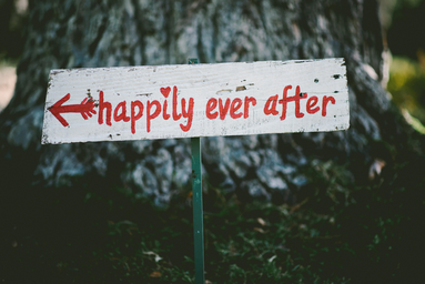 White and red sign saying \"happily ever after\" with arrow pointing left