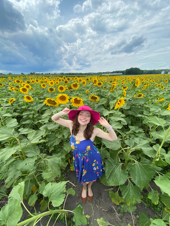 Camryn in a sunflower field with a pink hat