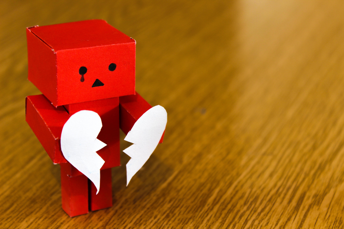Red block figure holding a white broken heart