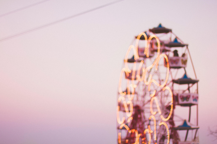 selective focus photograph of a ferris wheel against a pink sky