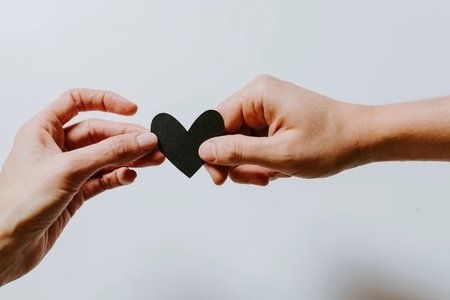 people exchanging a paper heart