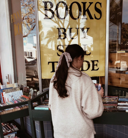 A girl\'s back profile as she looks at books outside a bookstore
