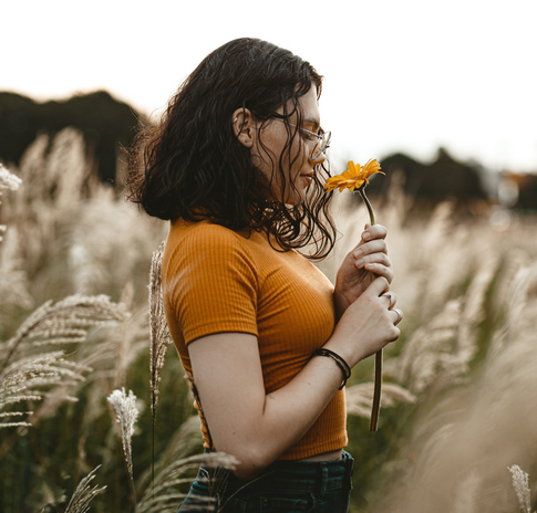 woman in field smelling flower