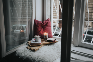 coffee, book and candle set by the window with a pillow