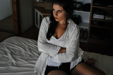 Angry woman sitting on bed with arms crossed