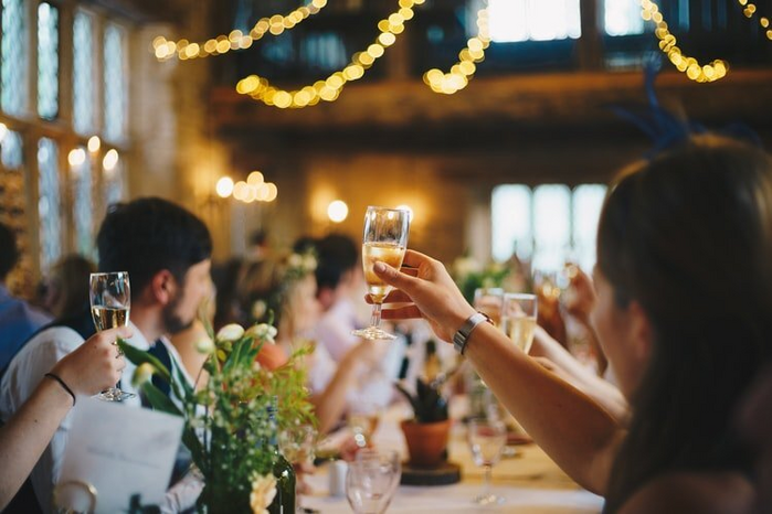 person raising glass for a toast by Unsplash