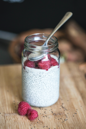 glass jar filled with chia seed pudding and raspberries