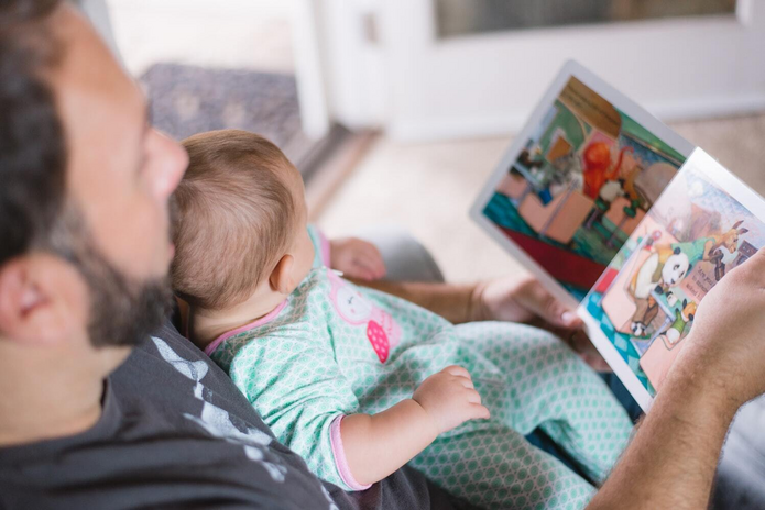Father reading a book to his baby by Unsplash