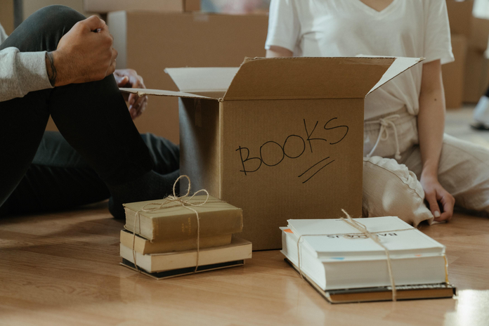 Box of books with humans on floor