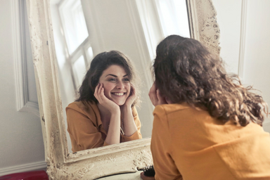 Orange shirt girl smiling in the mirror