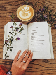 photo of an open poetry book and a coffee.