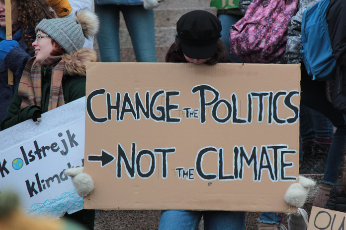sign reading \"change the politics not the climate\" at a climate protest