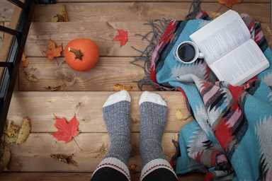 Cozy socks next to a book and a pumpkin