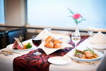 A table set with a fine dining meal with wine in a train dining car